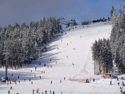 Der obere Abschnitt der Skipiste Hexenritt am Wurmberg ist verschneit und gefüllt mit Skifahrern. An der Seite ist der fahrende Lift zu sehen.